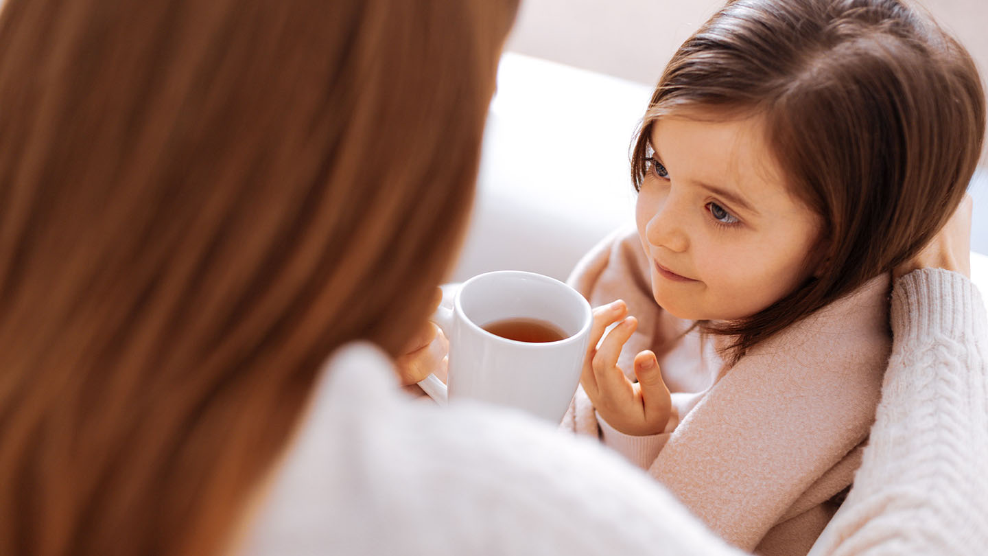 Mama siūlo arbatos savo dukrai, kuri serga gripu.