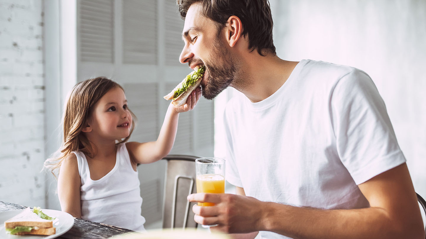 Tėvas ir vaikas mėgaujasi sumuštiniu.