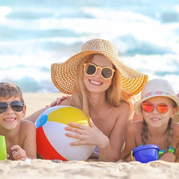 Vasara ir vaikų ligos; šeima pajūryje mėgaujasi paplūdimiu ir saule.