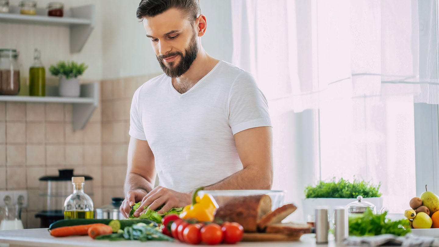 Vyras sportininkas virtuvėje ruošia sveiką valgį.